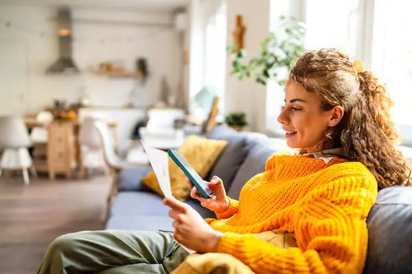 Frau im orangen Pullover liest Zeitung