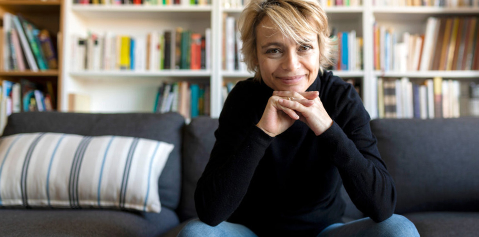 Frau sitzt auf einer Couch vor einem Buecherregal 960 x 475 Desktop